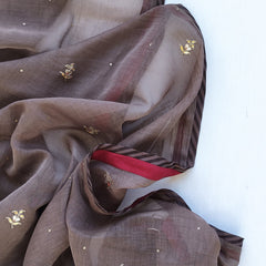 Dark brown fabric with gold gotapatti embroidery and a red ribbon on a white background.
